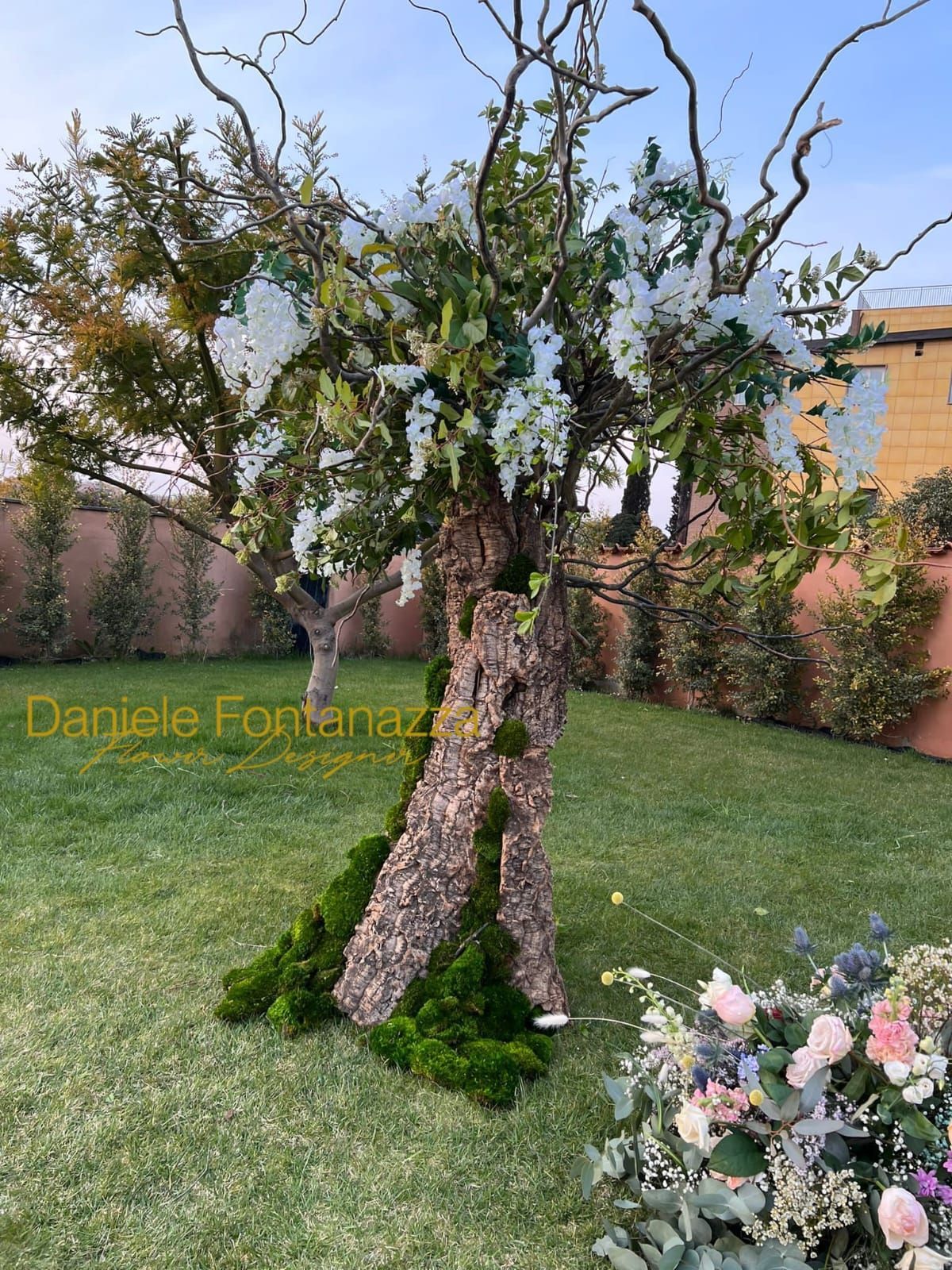 Albero decorativo con fiori bianchi e verde, in un giardino.