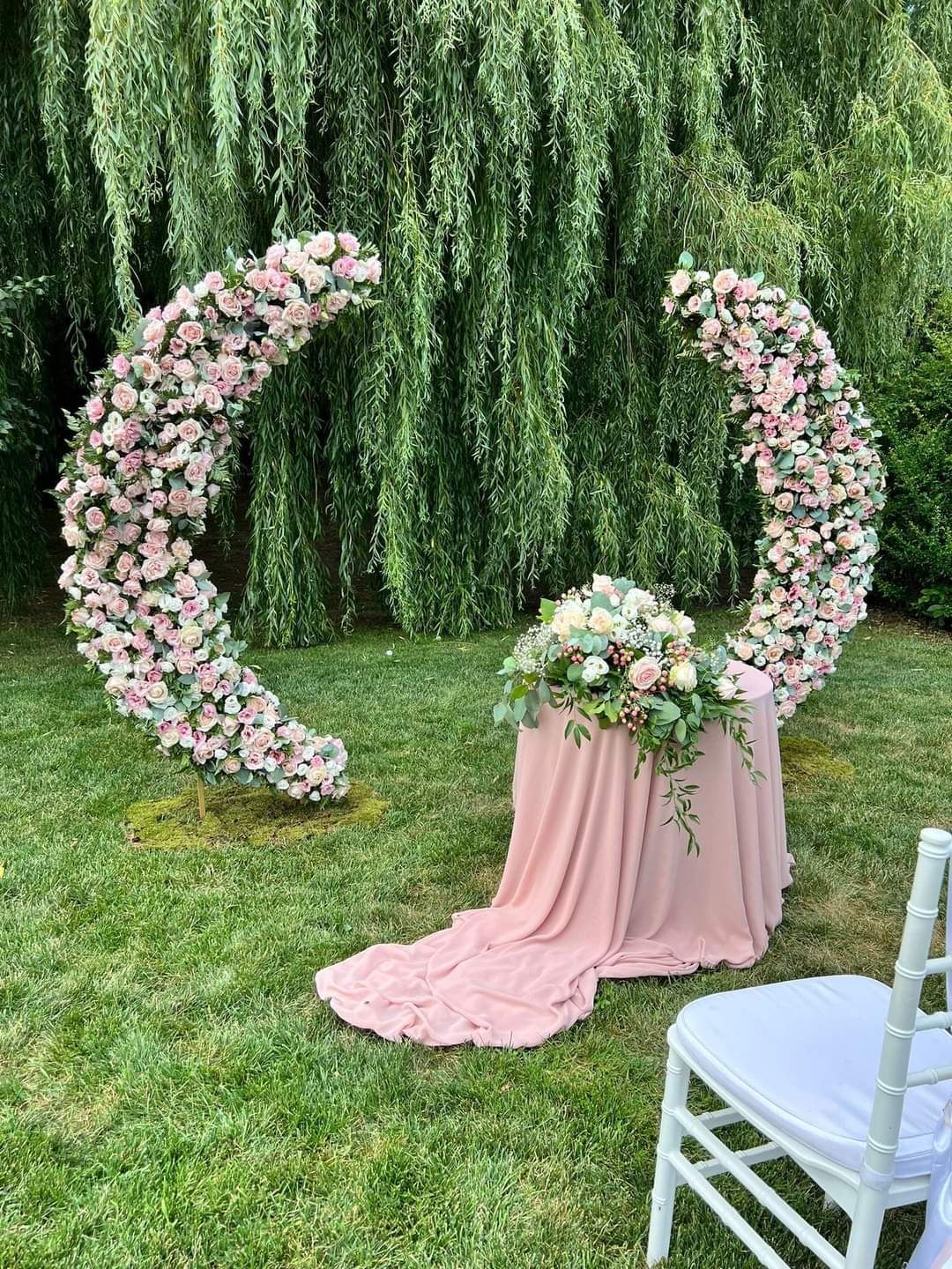 All'esterno, un arco floreale con tavolo drappeggiato e sedia bianca.