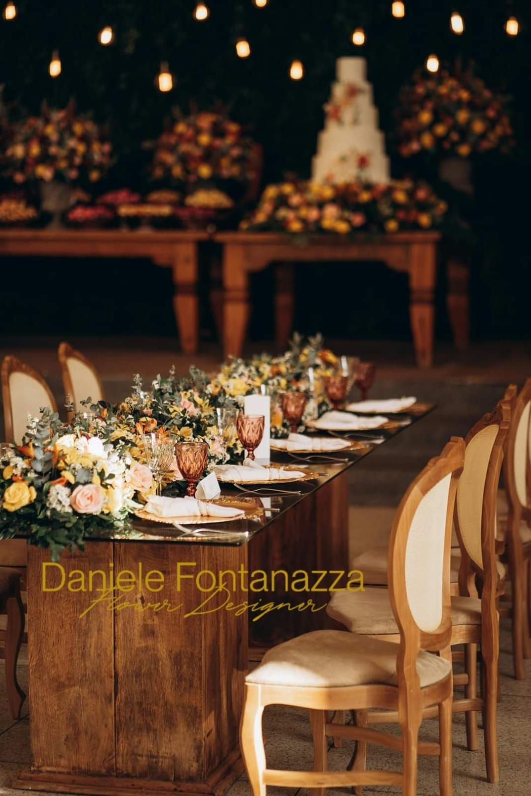 Apparecchiatura del tavolo del ricevimento di nozze con composizioni floreali, tavoli in legno rustico e sedie eleganti.