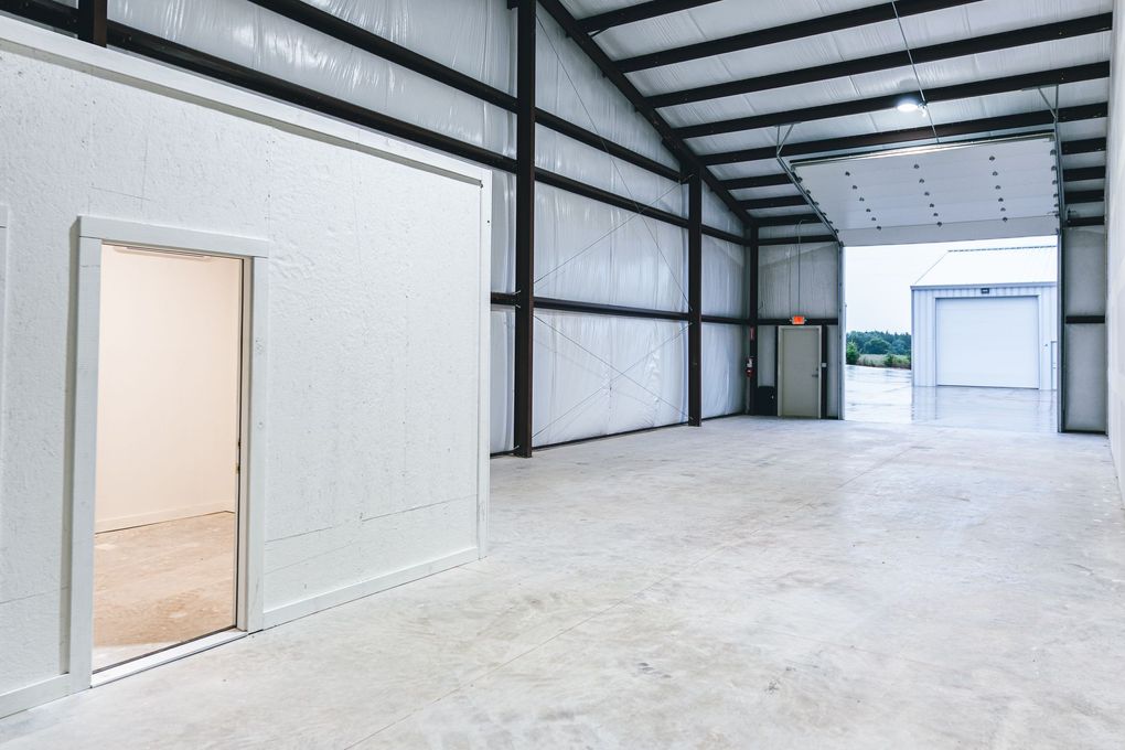 An orange truck is parked next to an office space in an empty garage