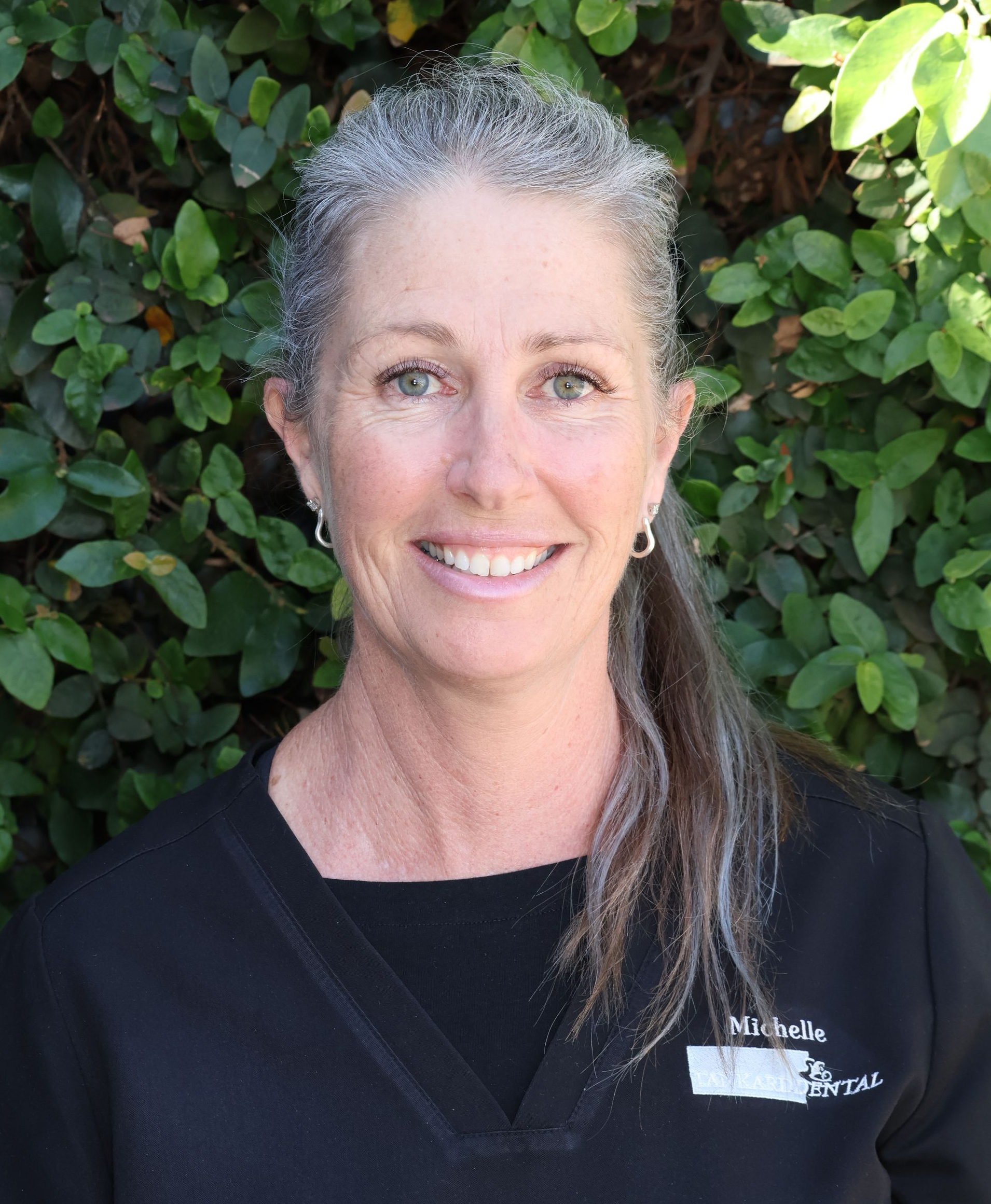 Woman with fair skin wearing a black uniform smiling at the camera. Name tag reads 