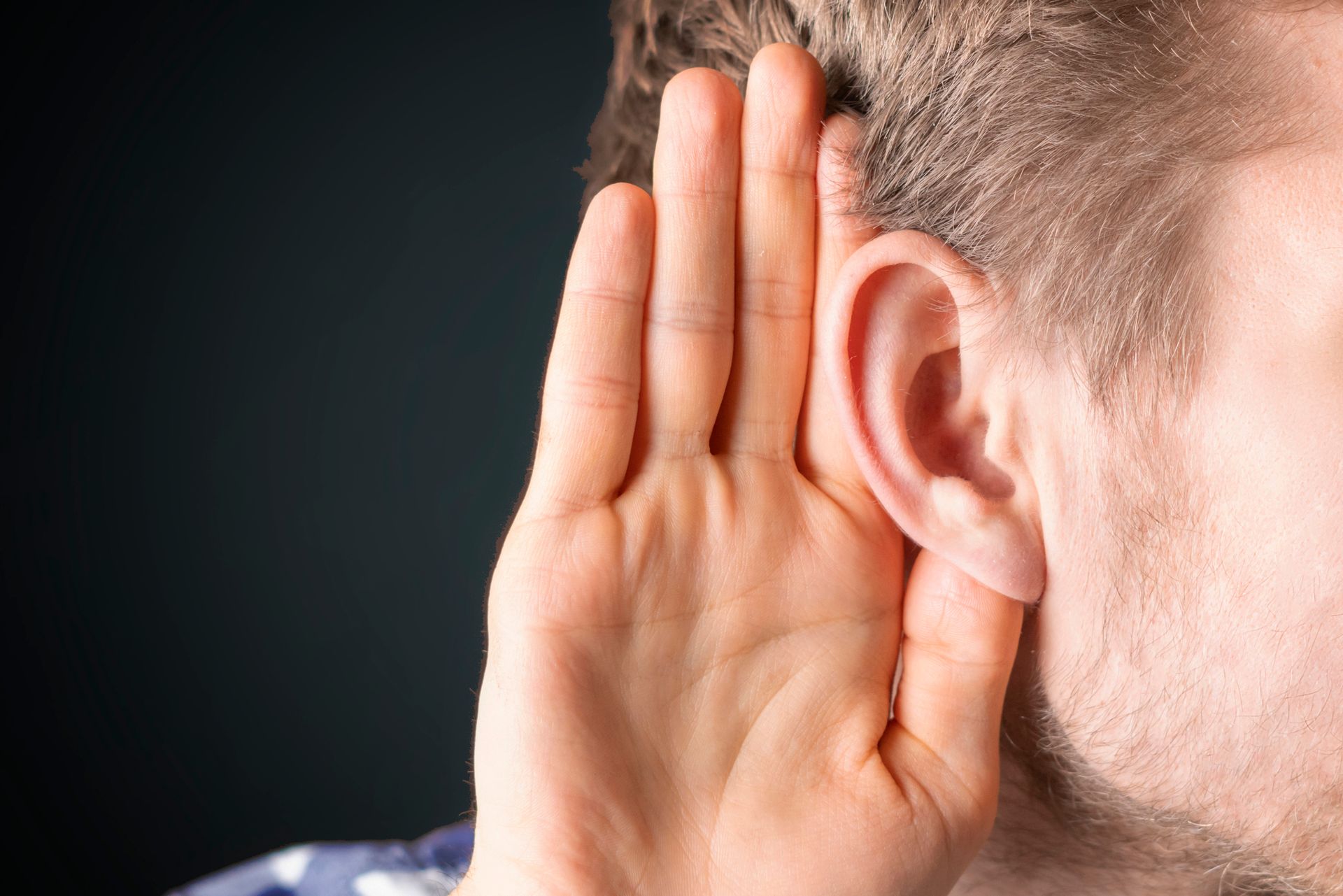 A person holding his hand to his ear