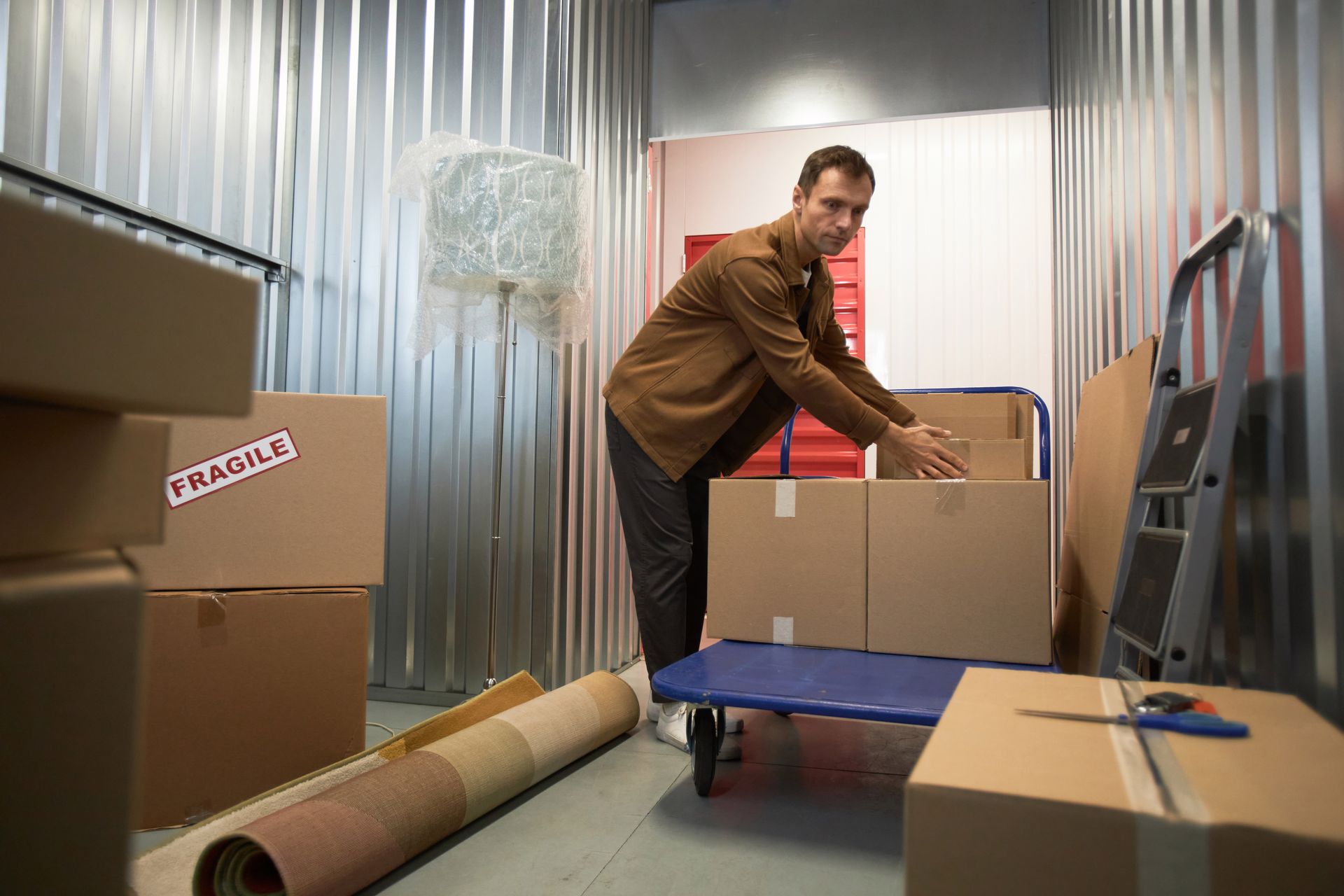 A man is organizing boxes inside a clean, ground-level self-storage unit in Chesterfield, VA. A man is organizing boxes inside a clean, ground-level self-storage unit in Chesterfield, VA.