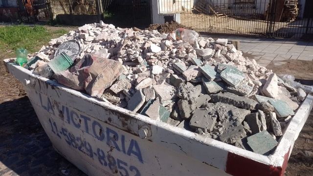 Contenedor lleno de hormigón roto y escombros en una zona de construcción al aire libre.
