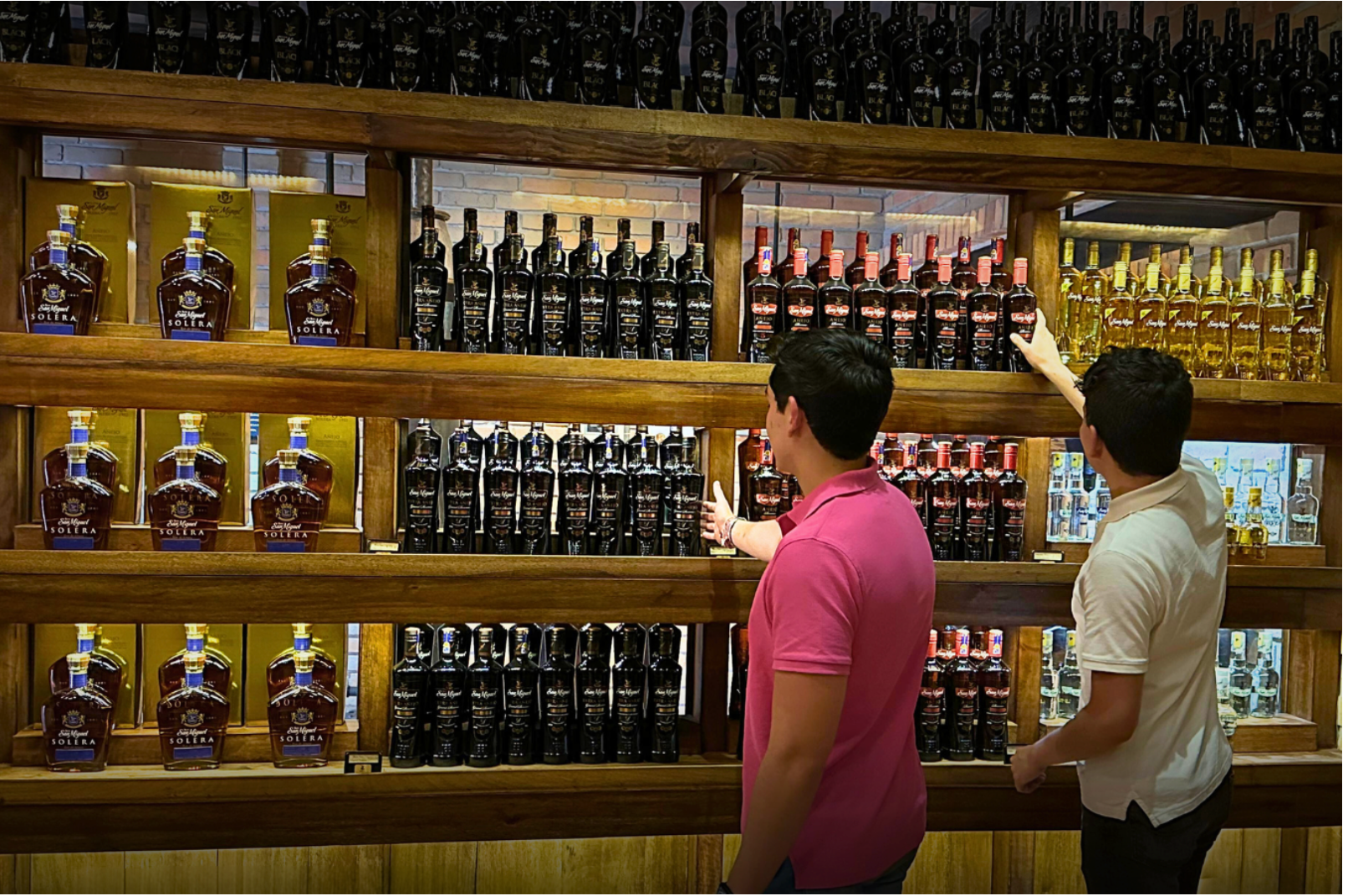 Two men are looking at bottles of Ron San Miguel in Cava San Miguel