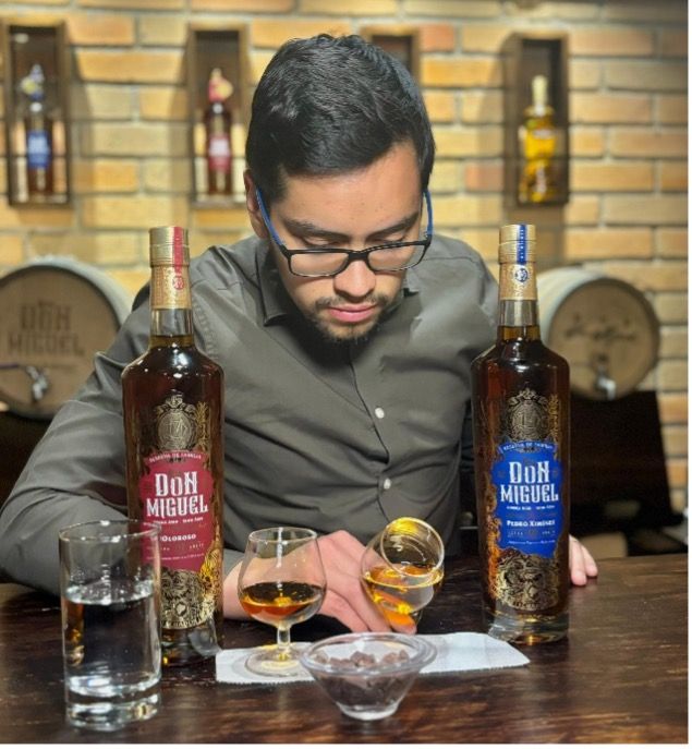 A man sitting at a table with two bottles of don miguel
