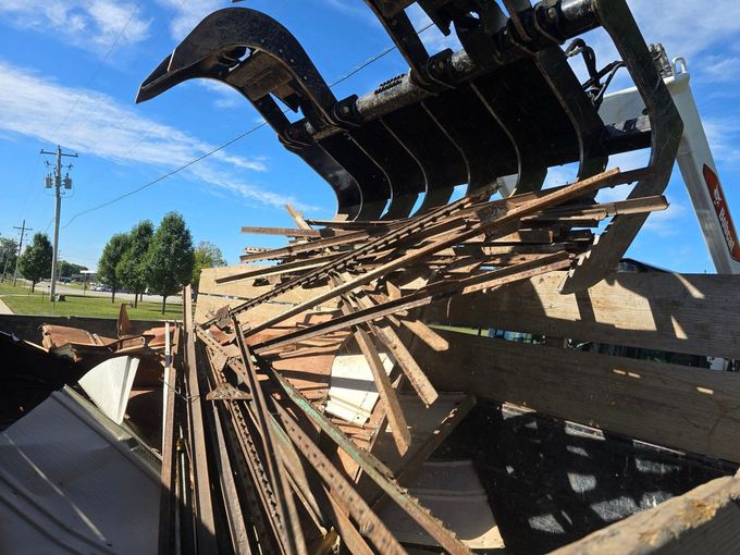 A pile of wood is being removed from a building by a machine