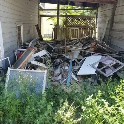 A pile of trash is sitting in front of a house.