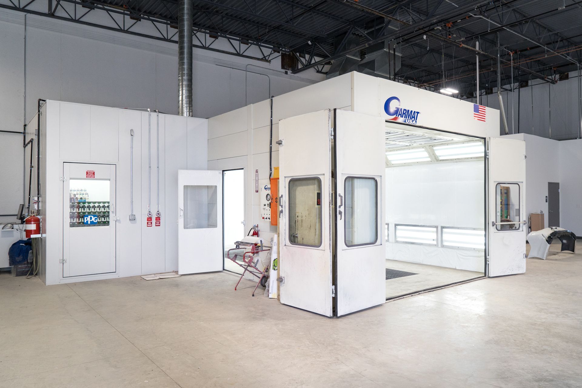 A large white paint booth in a large warehouse.