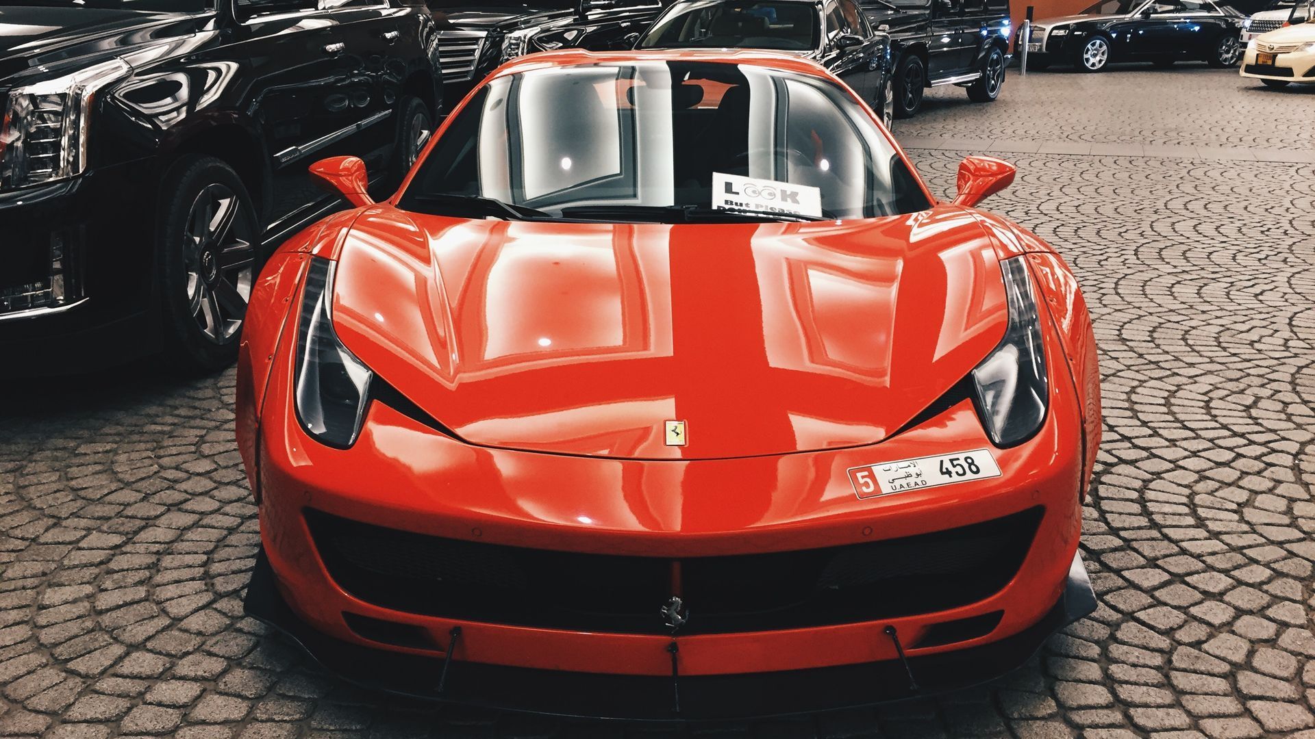 A red ferrari sports car is parked on a cobblestone street.