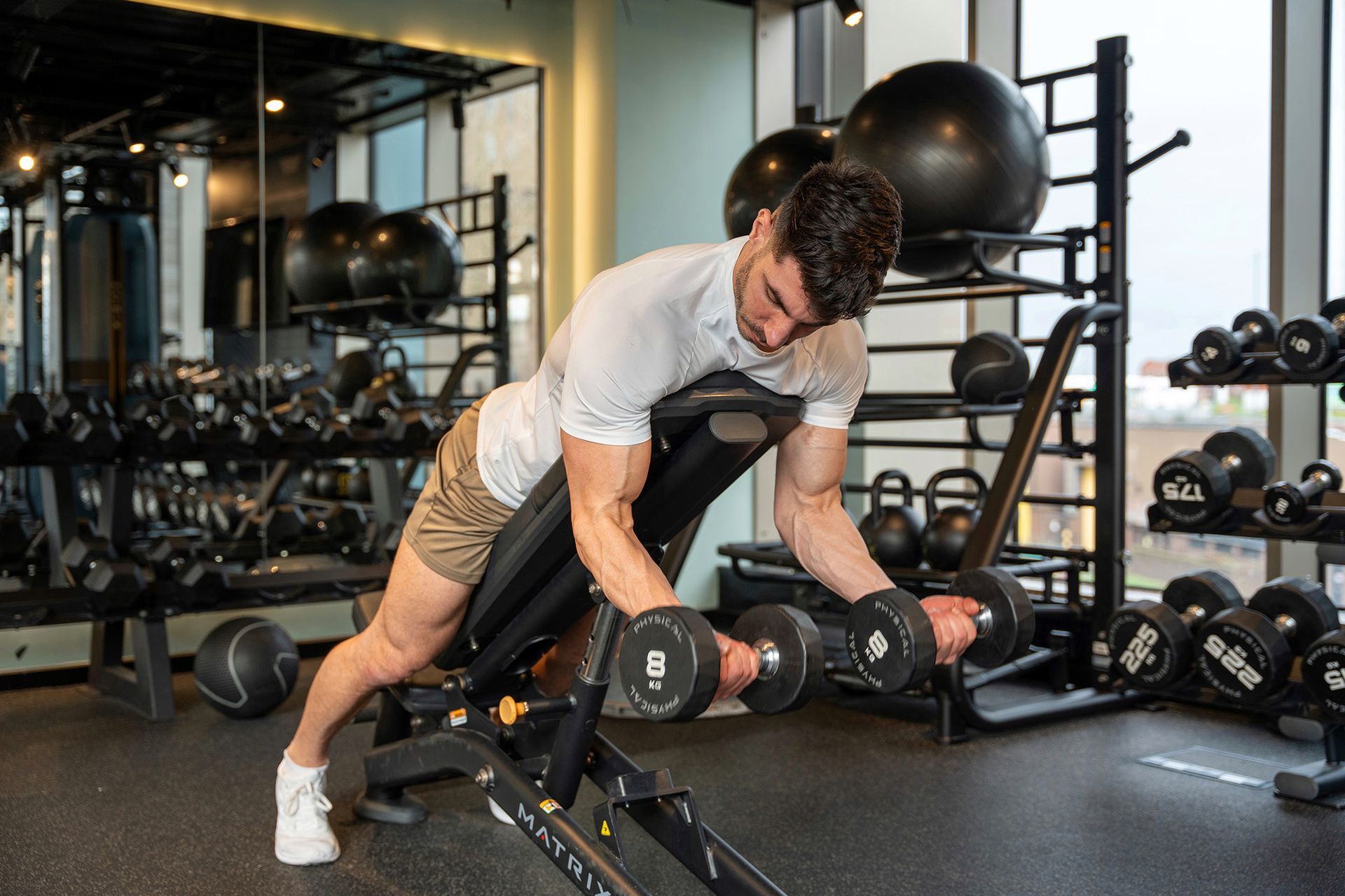 Person lifting weights as part of a strength training routine to build muscle while losing fat.