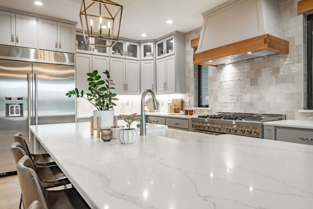 Modern kitchen with white countertops, stainless steel appliances, and a wooden range hood.