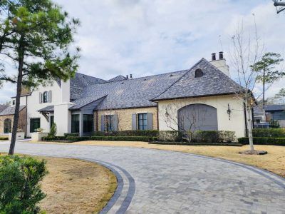 Upscale house with a slate roof, stone facade, and circular driveway.