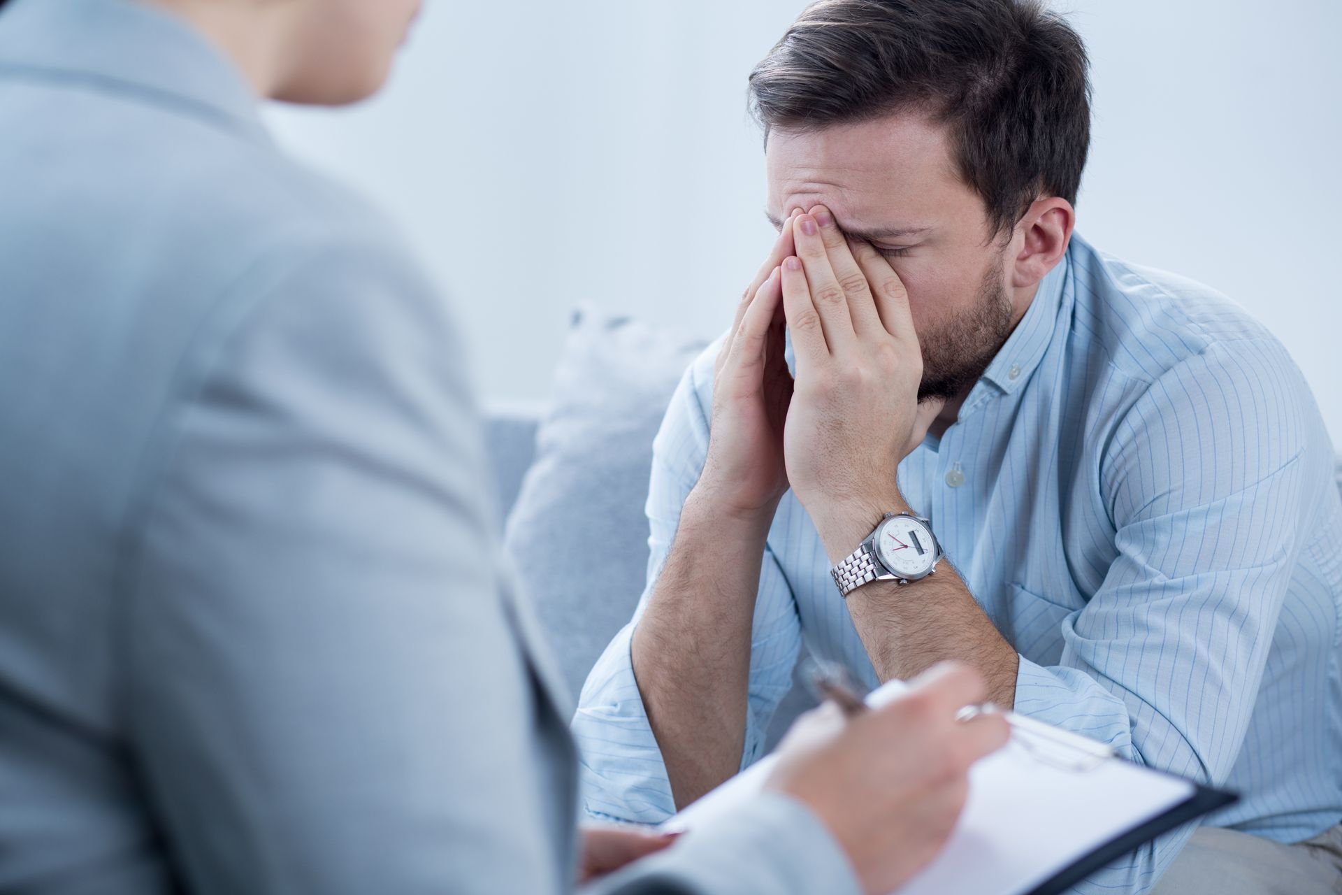 Man sitting on a couch with his face in his hands during a counseling session