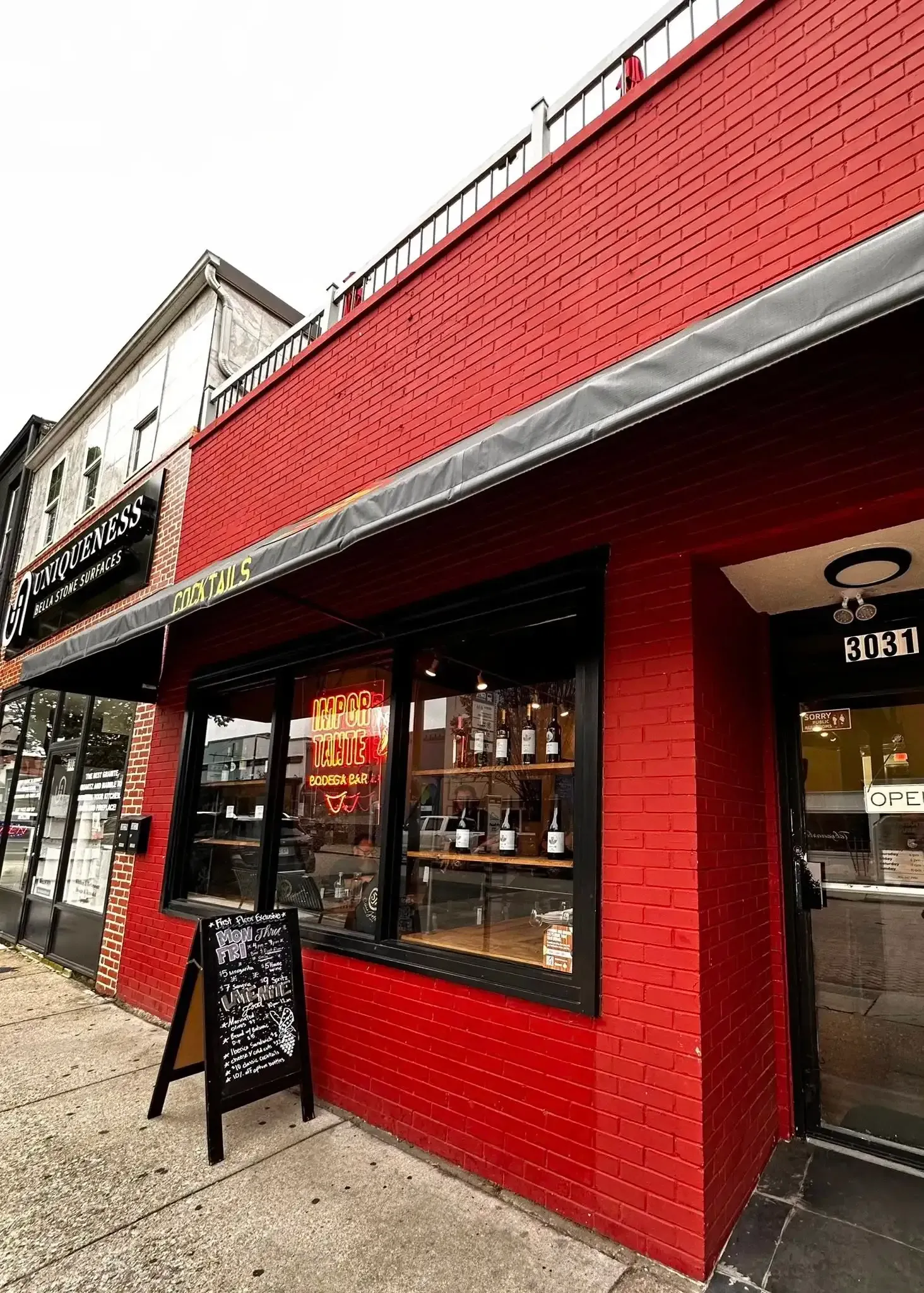 Red brick building with black awning, sign and menu; shop entrance visible on the right.