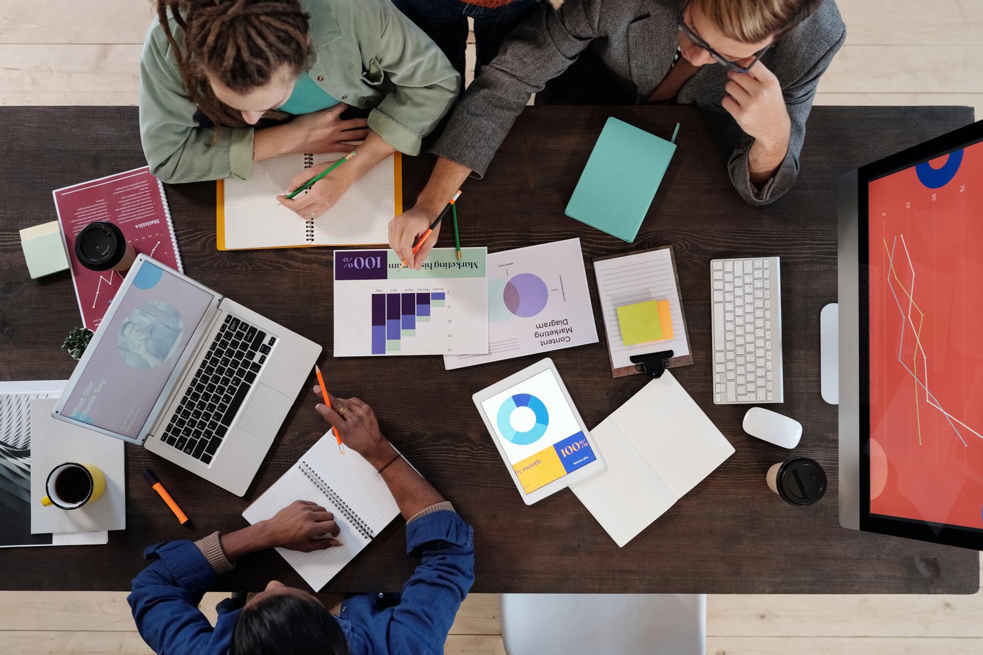 A group of people are sitting around a table with laptops and papers.