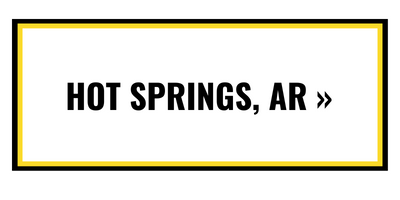 A rectangular button with a white background, black border, and yellow inner frame, featuring the text 