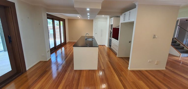 An Empty Kitchen With Hardwood Floors And White Cabinets — A1 Cleaner Carpets N Homecare In Yungaburra, QLD