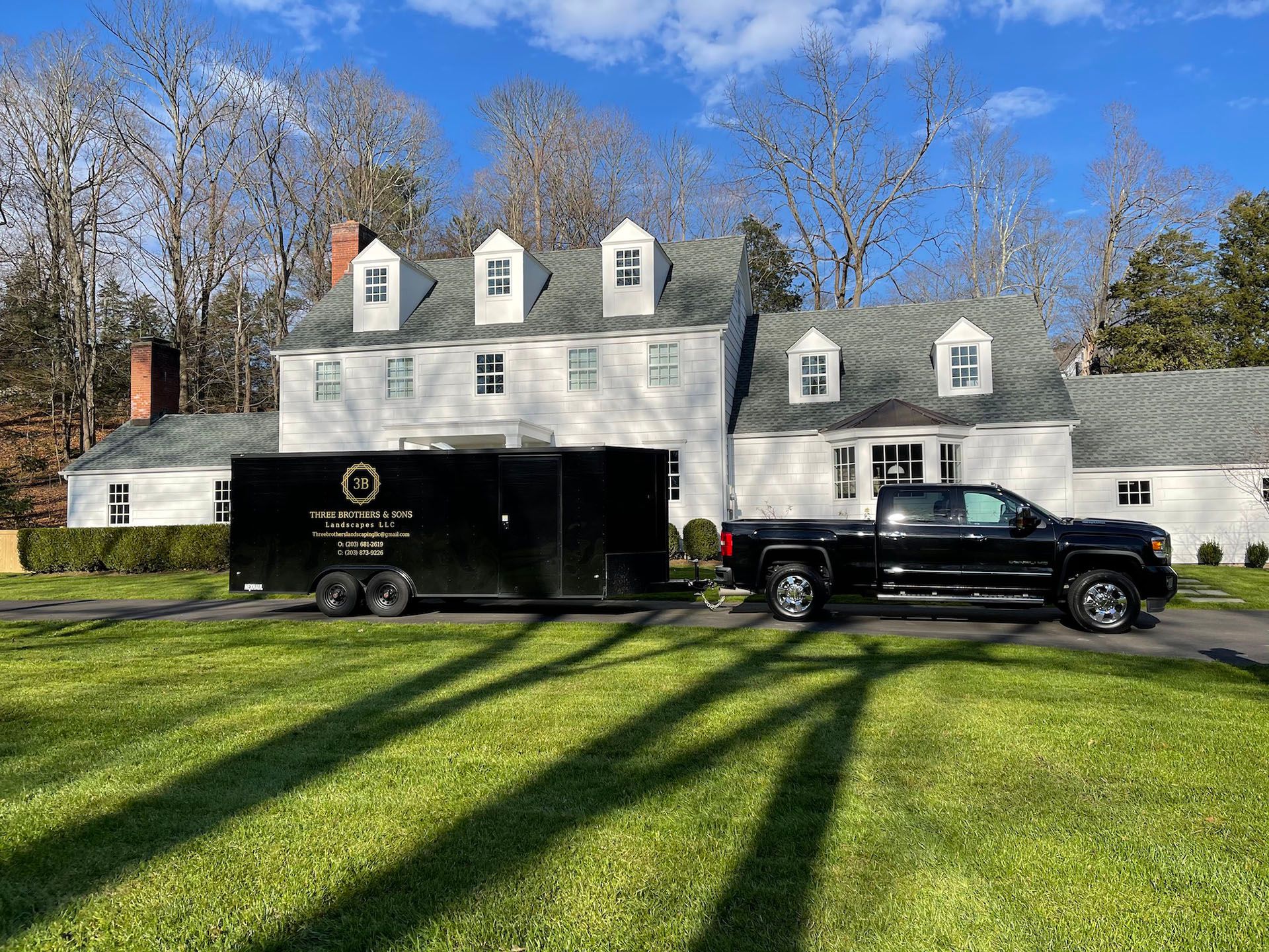 A black truck is parked in front of a large white house.
