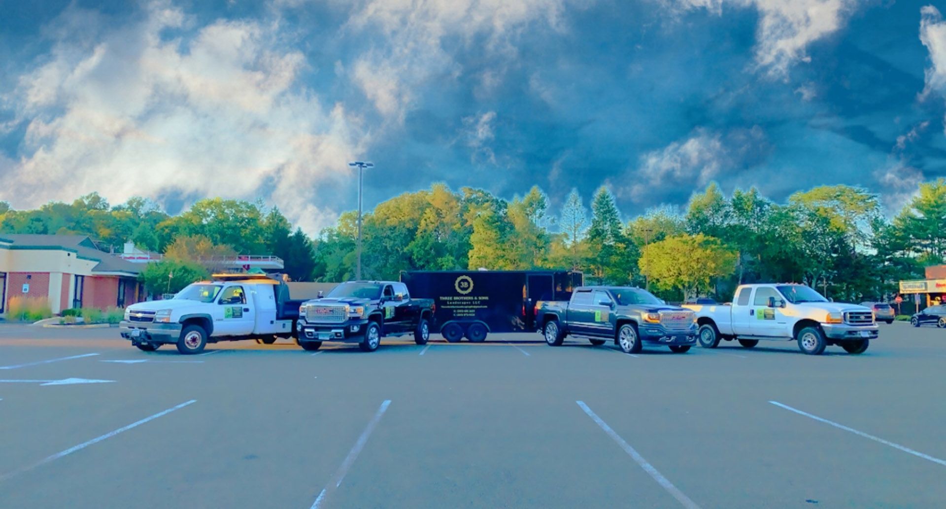 A row of trucks are parked in a parking lot.