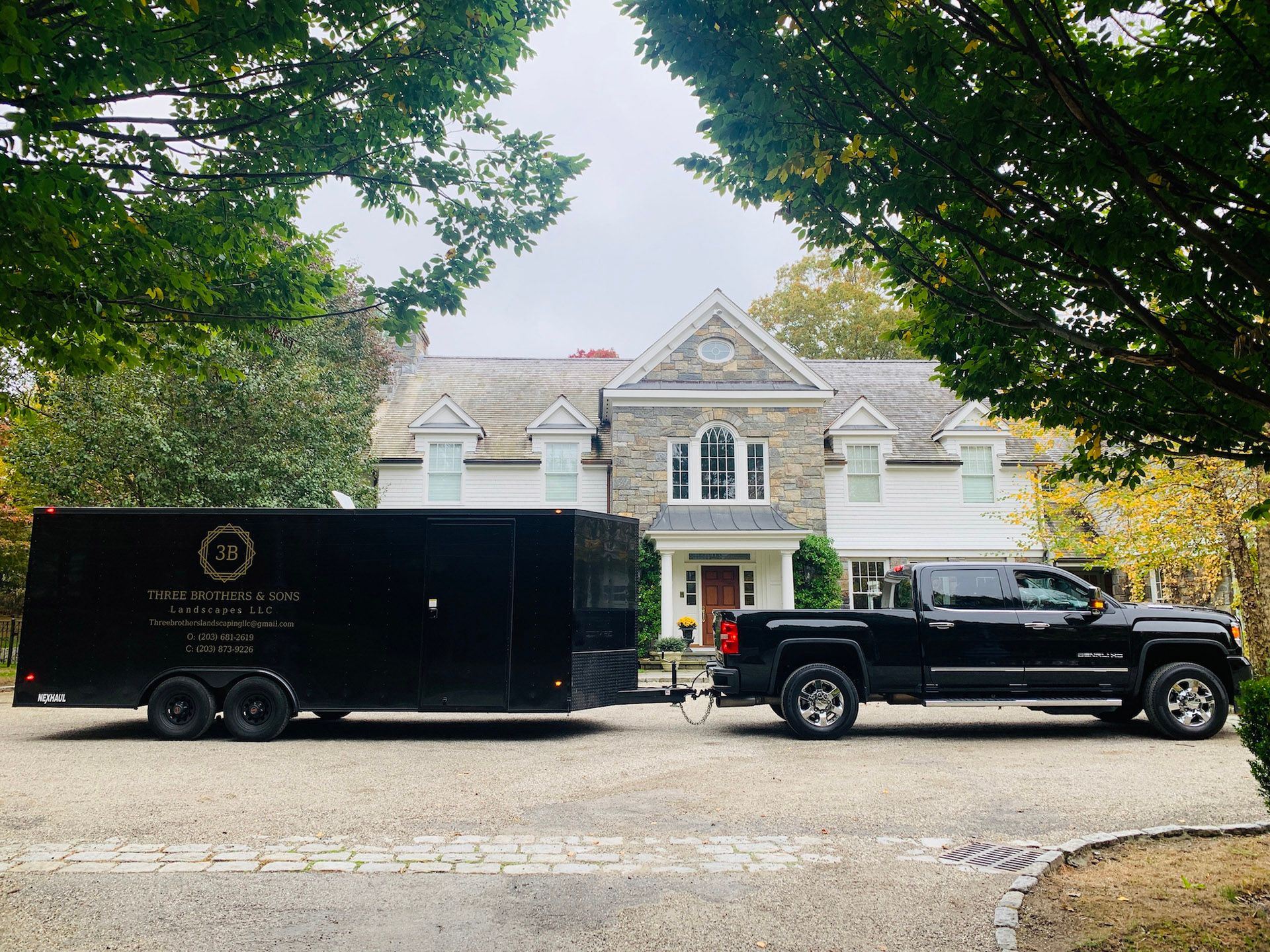 A truck and trailer are parked in front of a large house.