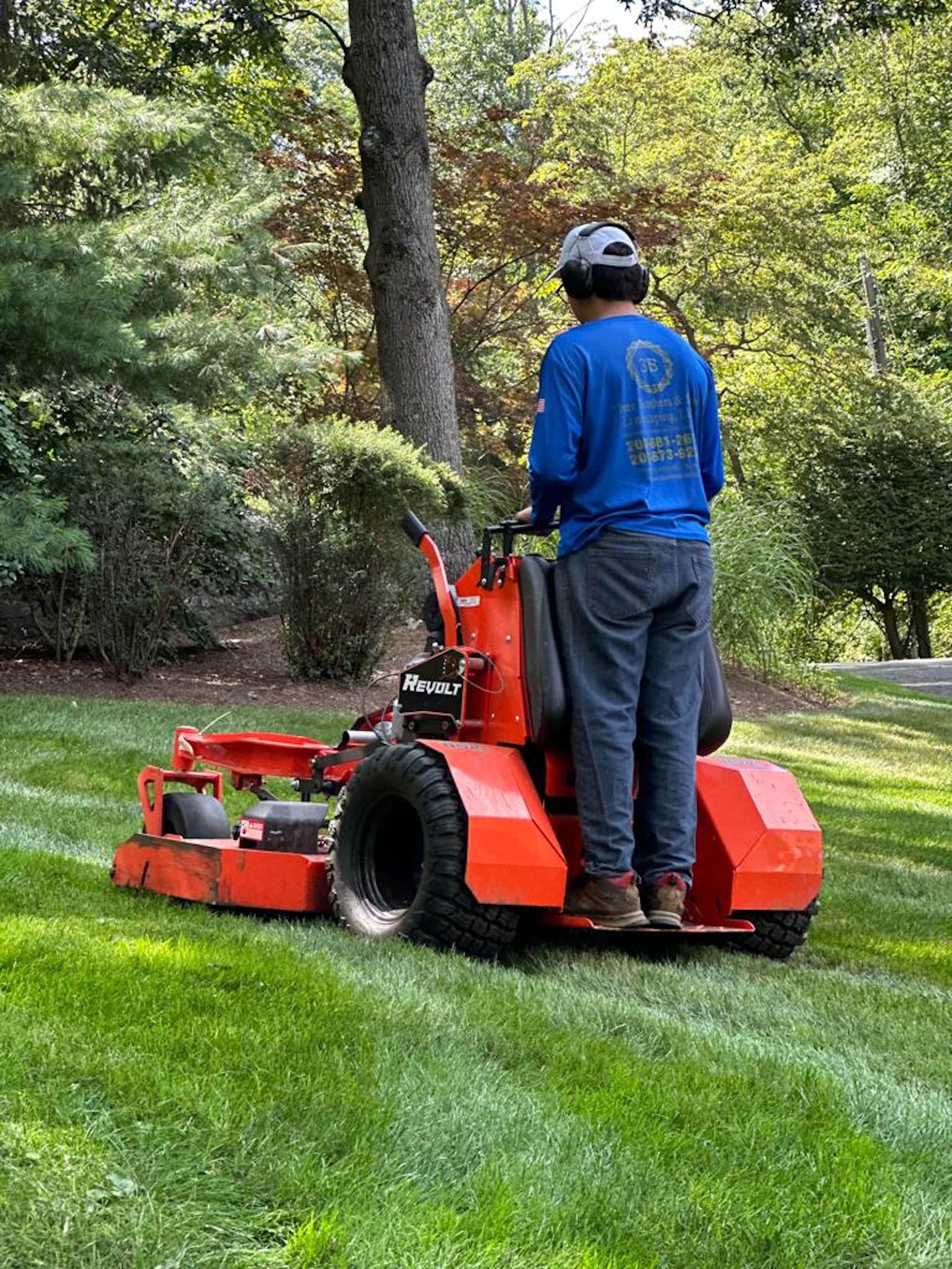 A man is riding a lawn mower on a lush green lawn.