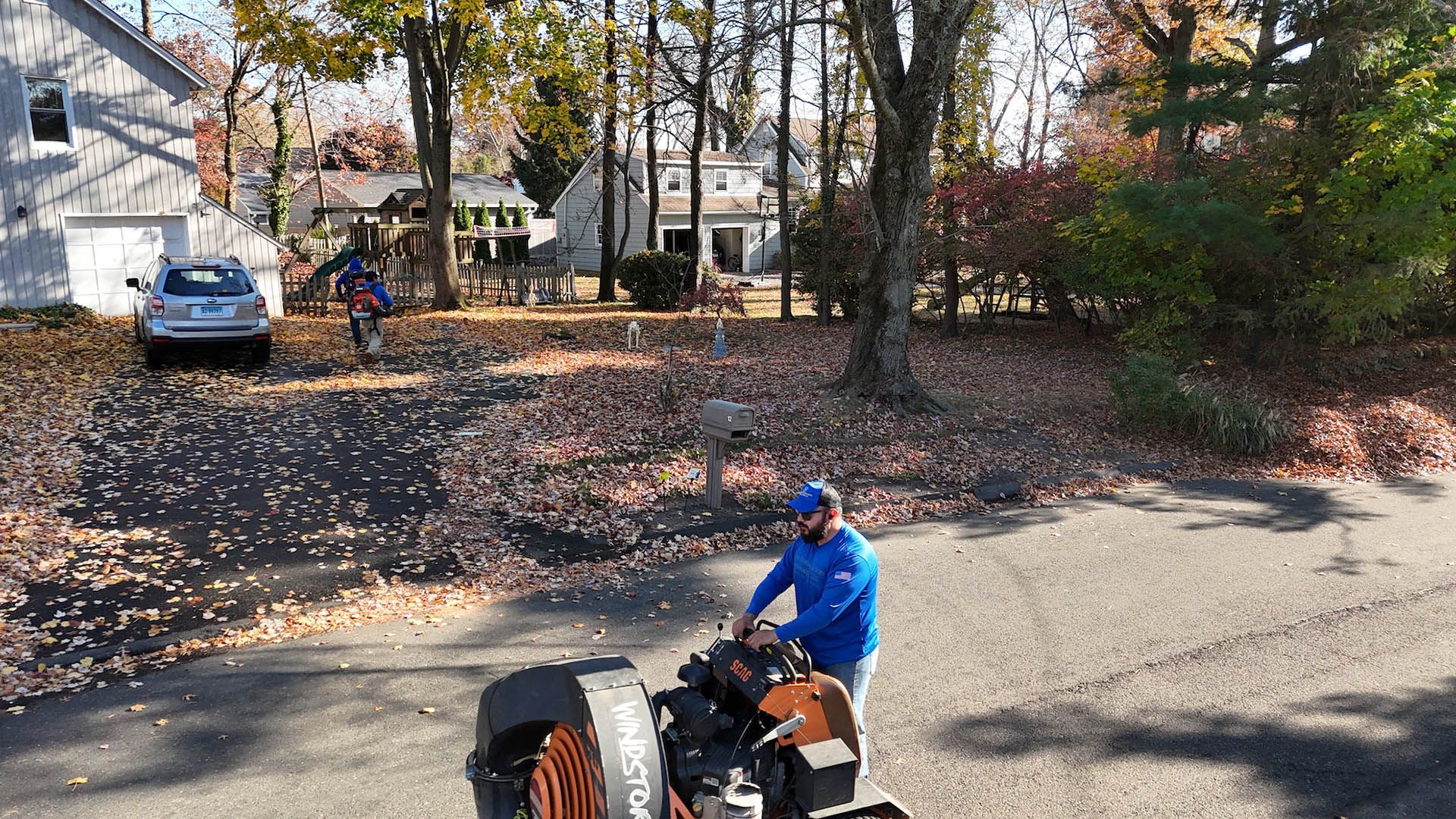 A man is using a leaf blower in a driveway.