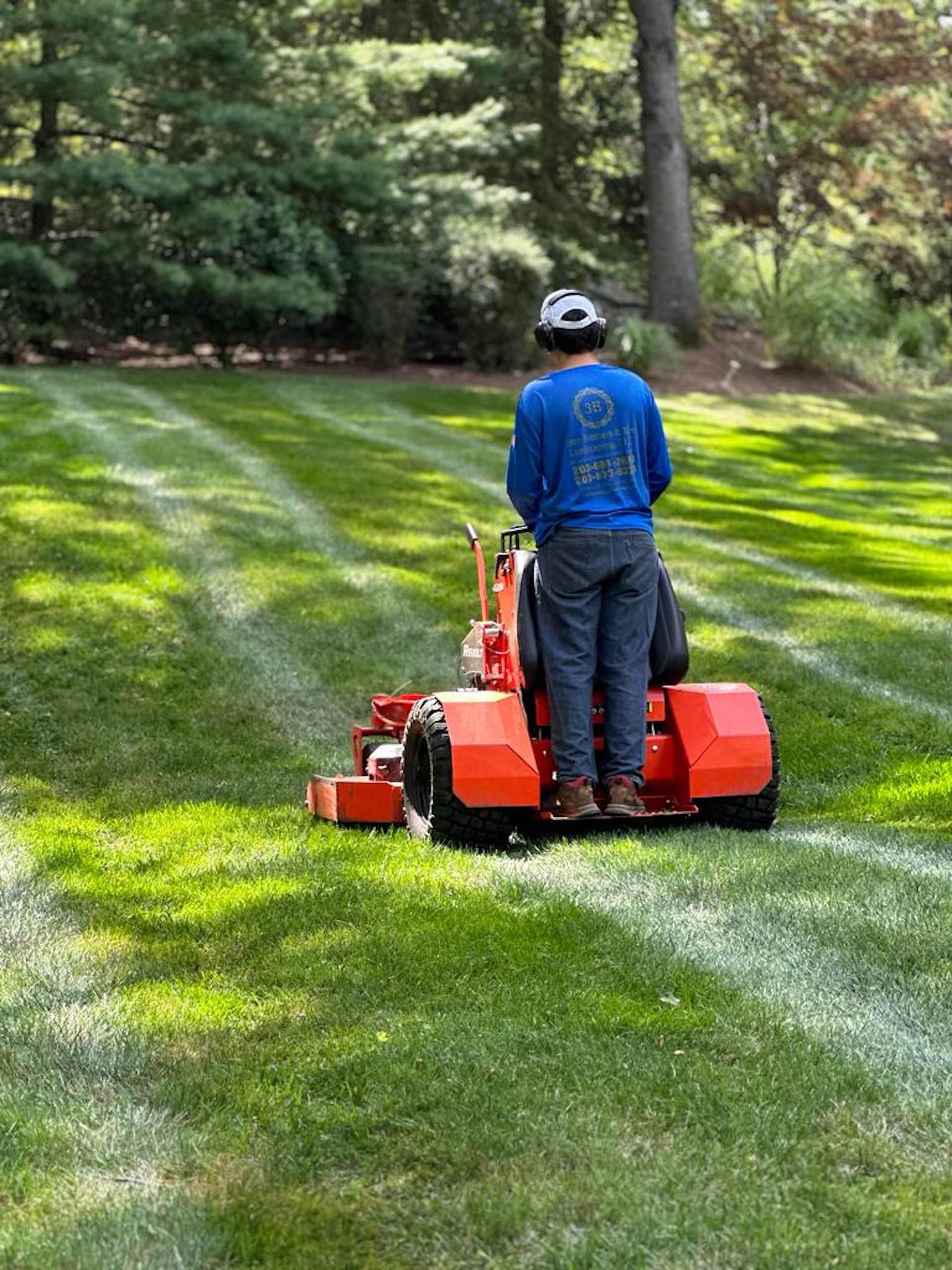 A man is riding a lawn mower on a lush green lawn.