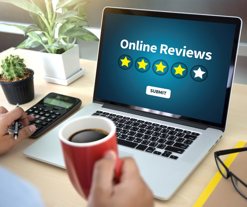A person is holding a cup of coffee in front of a laptop that says online reviews