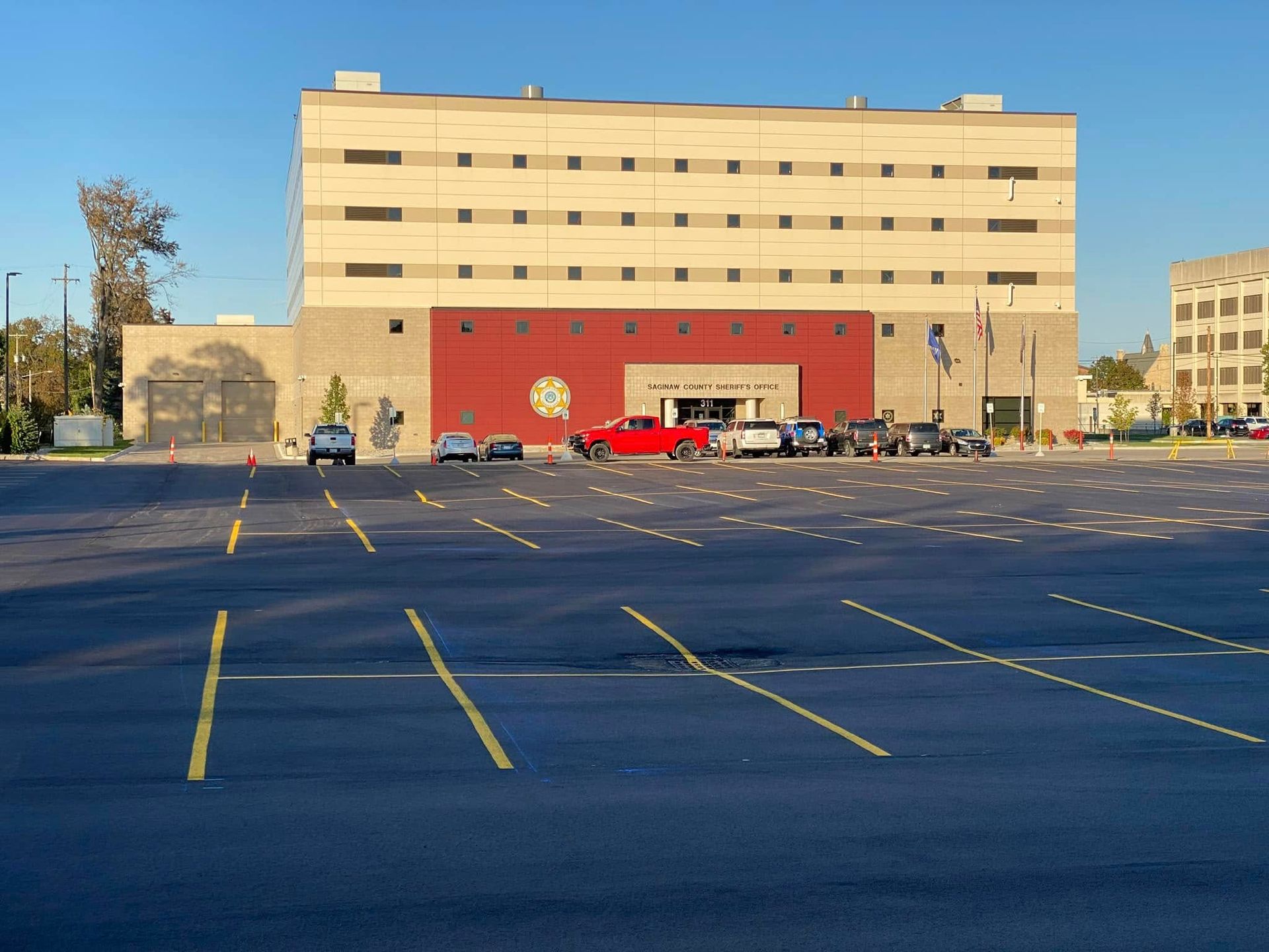Exterior view of a multi-story building with a large parking lot. Red and tan brick facade, cars parked in front. Exterior view of a multi-story building with a large parking lot. Red and tan brick facade, cars parked in front.