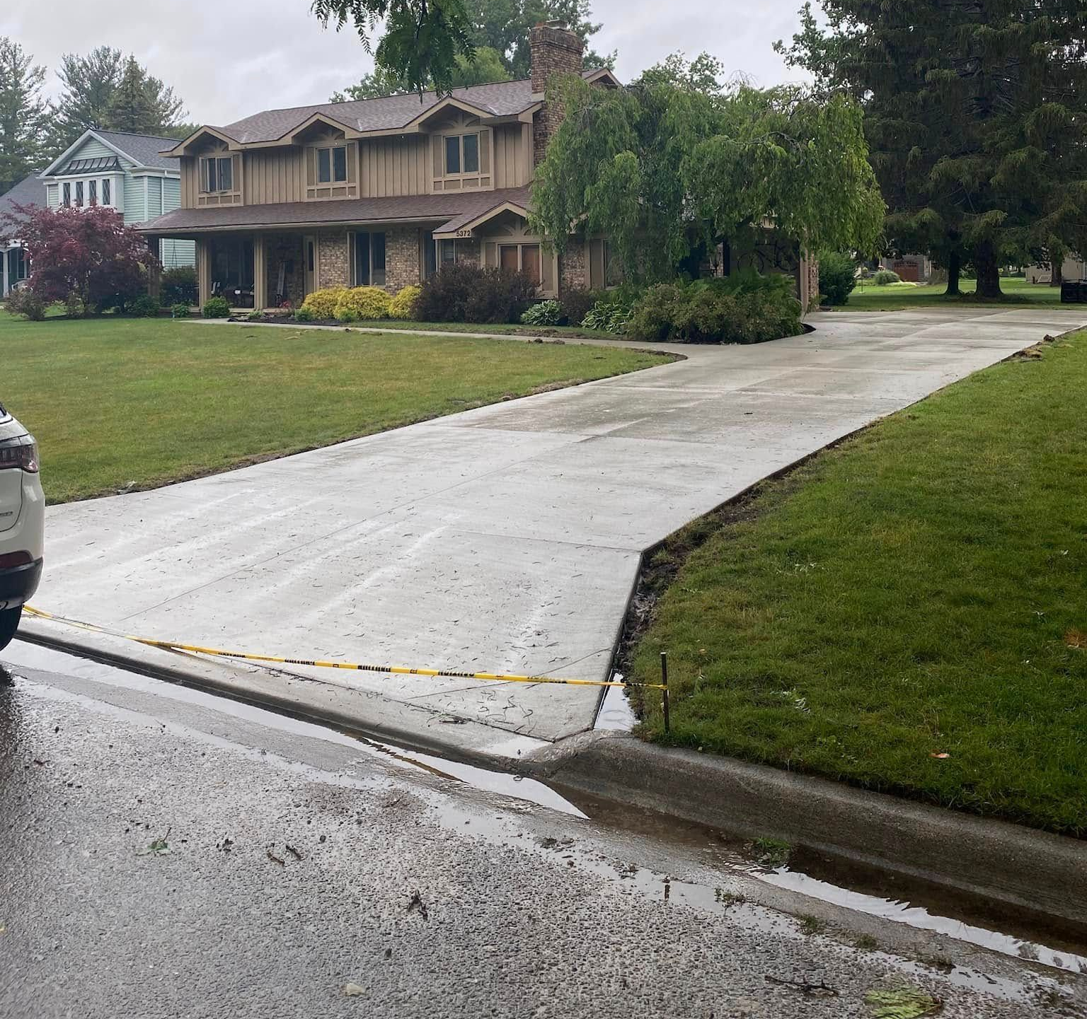 Driveway leading to a large house with a tan exterior and lush green lawn on a cloudy day. Driveway leading to a large house with a tan exterior and lush green lawn on a cloudy day.