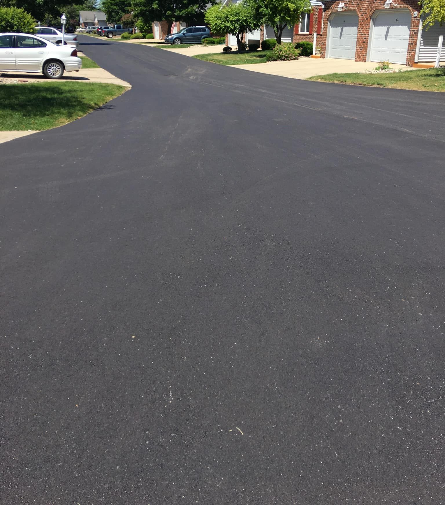 Newly paved asphalt road in residential neighborhood on a sunny day. Newly paved asphalt road in residential neighborhood on a sunny day.