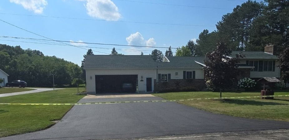 House with black asphalt driveway and garage, trees, and blue sky. House with black asphalt driveway and garage, trees, and blue sky.