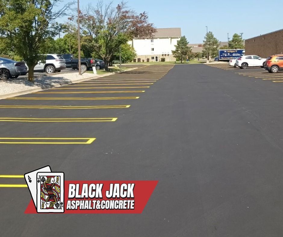 Newly paved asphalt parking lot with painted yellow lines.