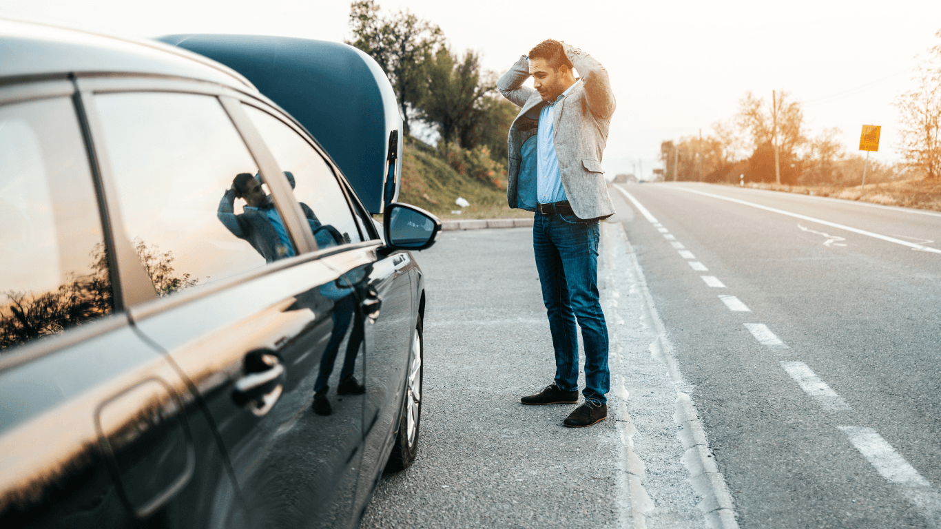 A broke down car with a man looking under the hood. 