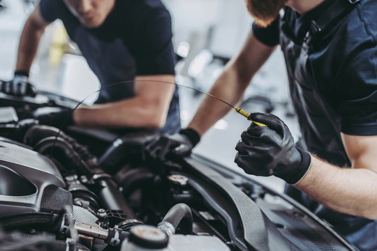 Two mechanics performing an oil change at someones home. 