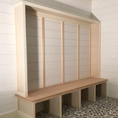 A wooden bench is sitting in a room next to a wall.