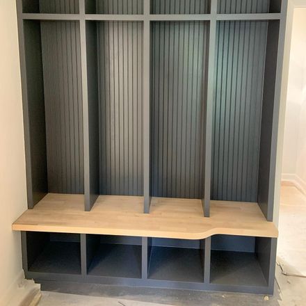 A gray locker with a wooden bench underneath it