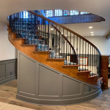 A wooden spiral staircase with a metal railing in a living room.