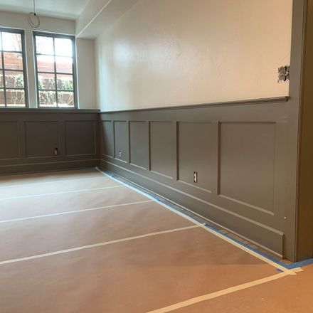 A room with gray paneling and a blue tape on the floor.