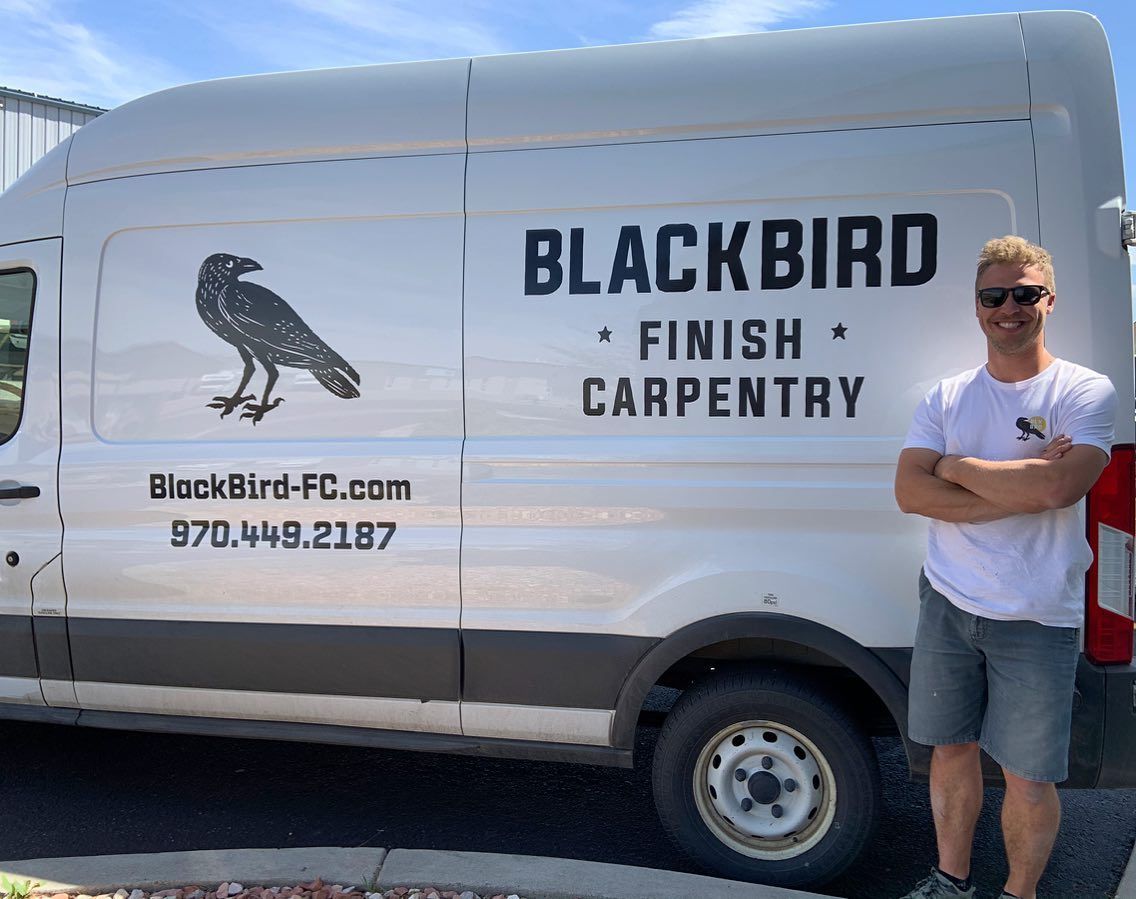 A man is standing in front of a blackbird finish carpentry van