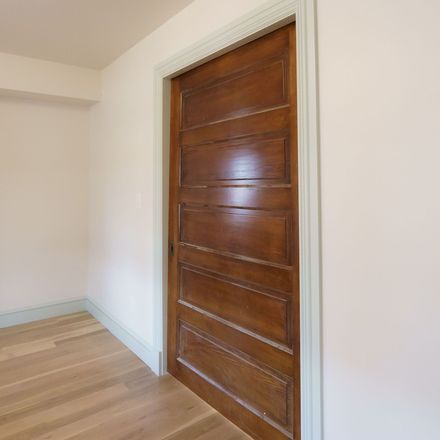A wooden door in an empty room with white walls
