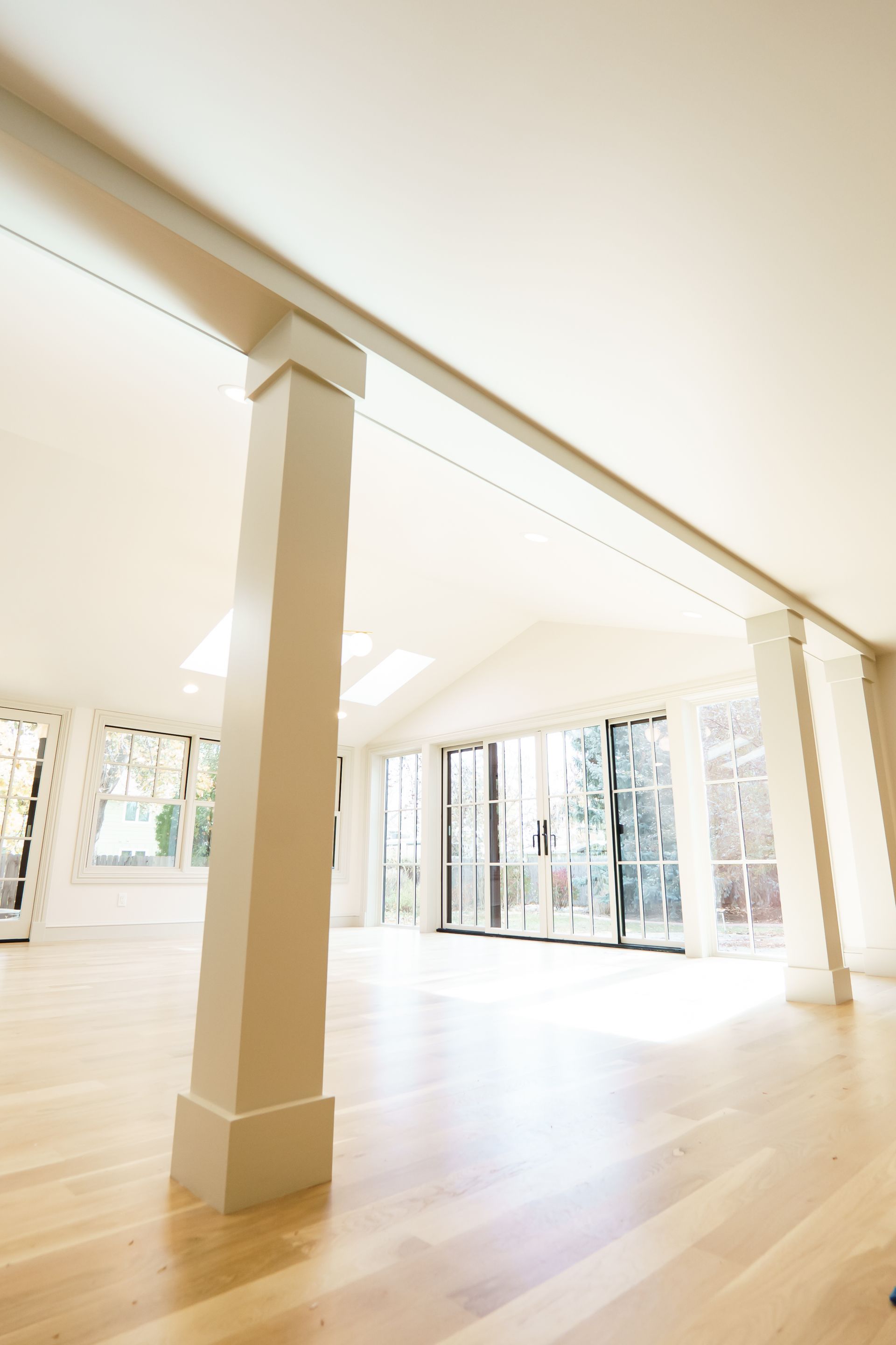 A large empty room with hardwood floors and white columns