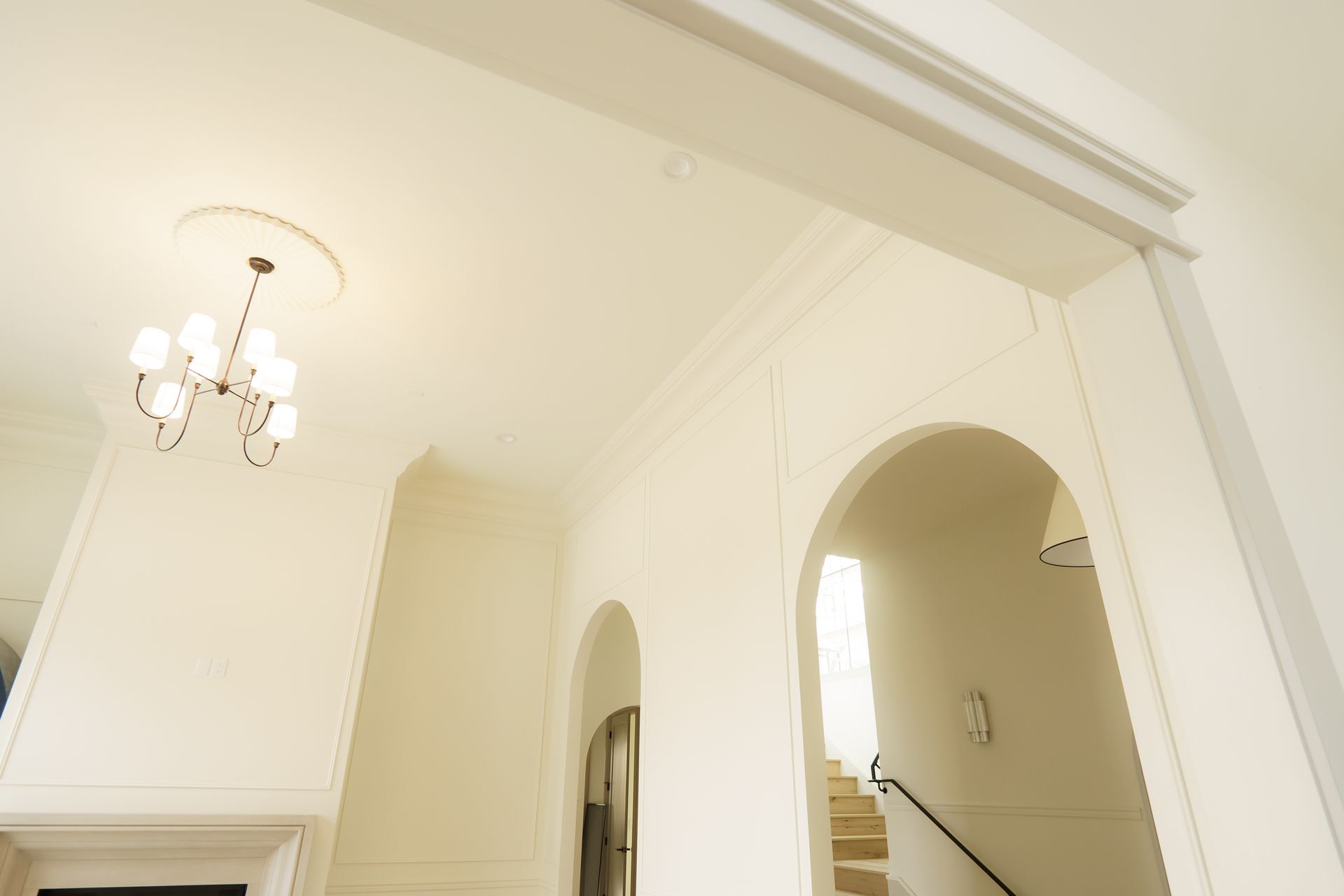 A hallway with arches and stairs and a chandelier hanging from the ceiling