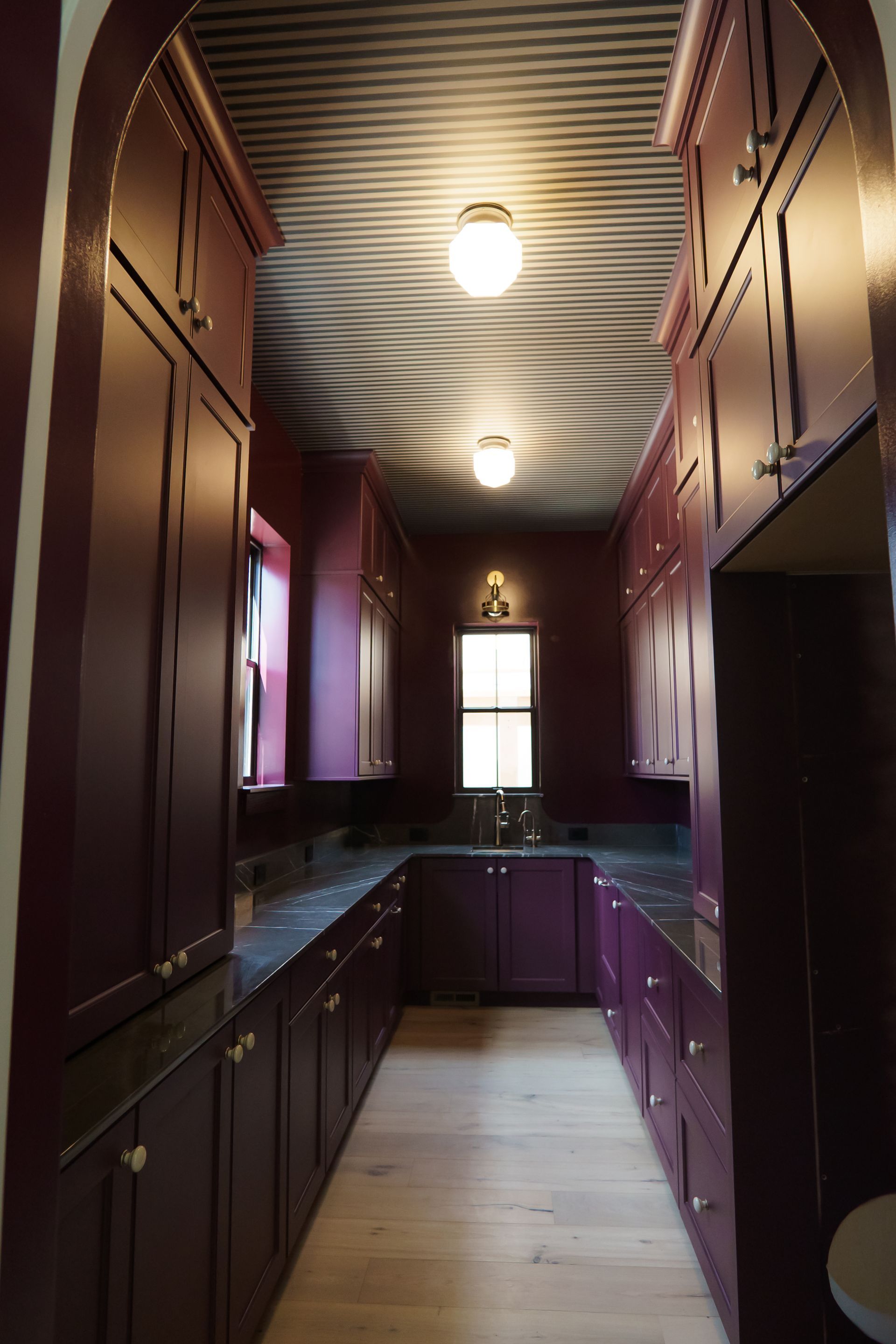 A kitchen with purple cabinets and a striped ceiling
