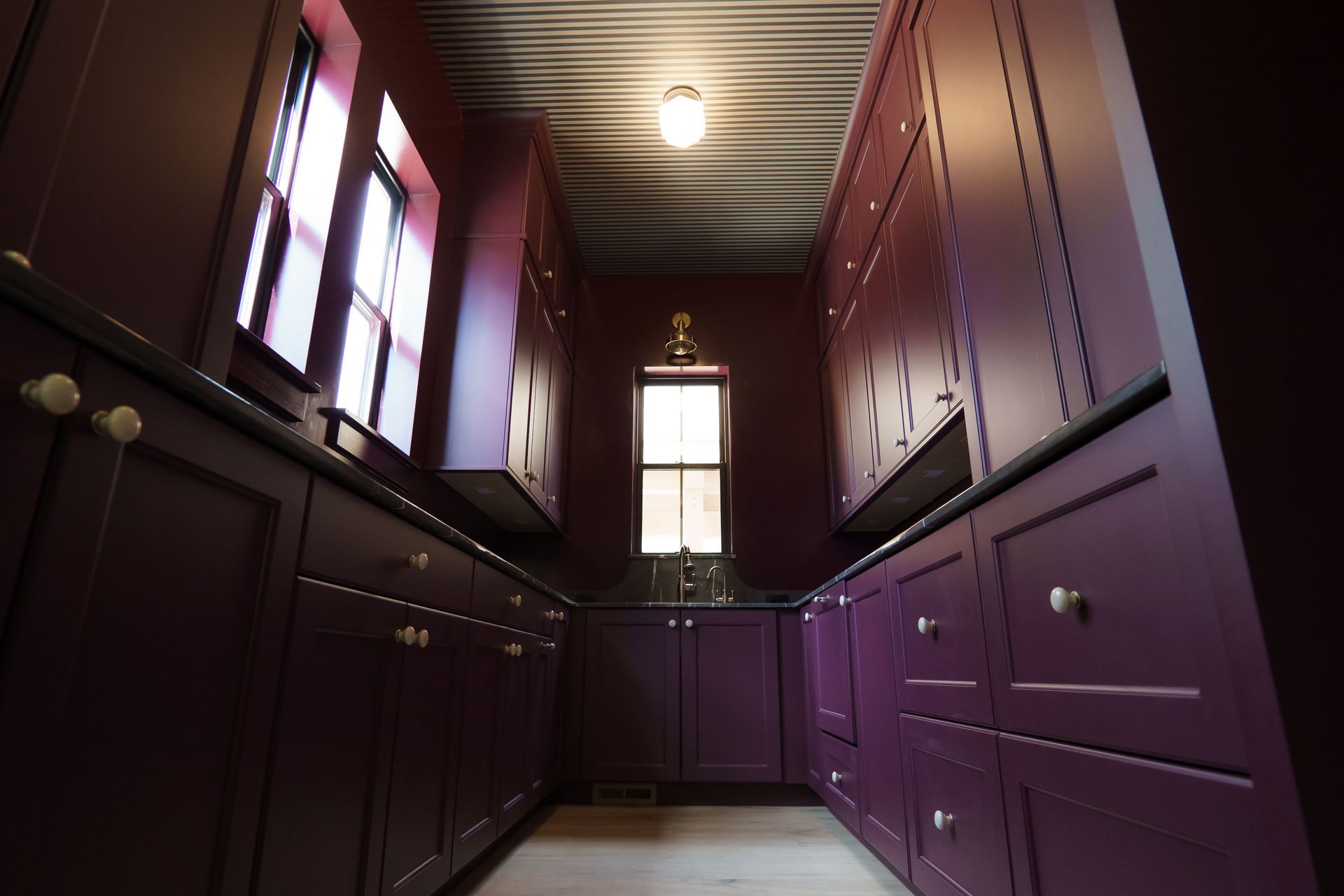 A kitchen with purple cabinets and drawers and a window