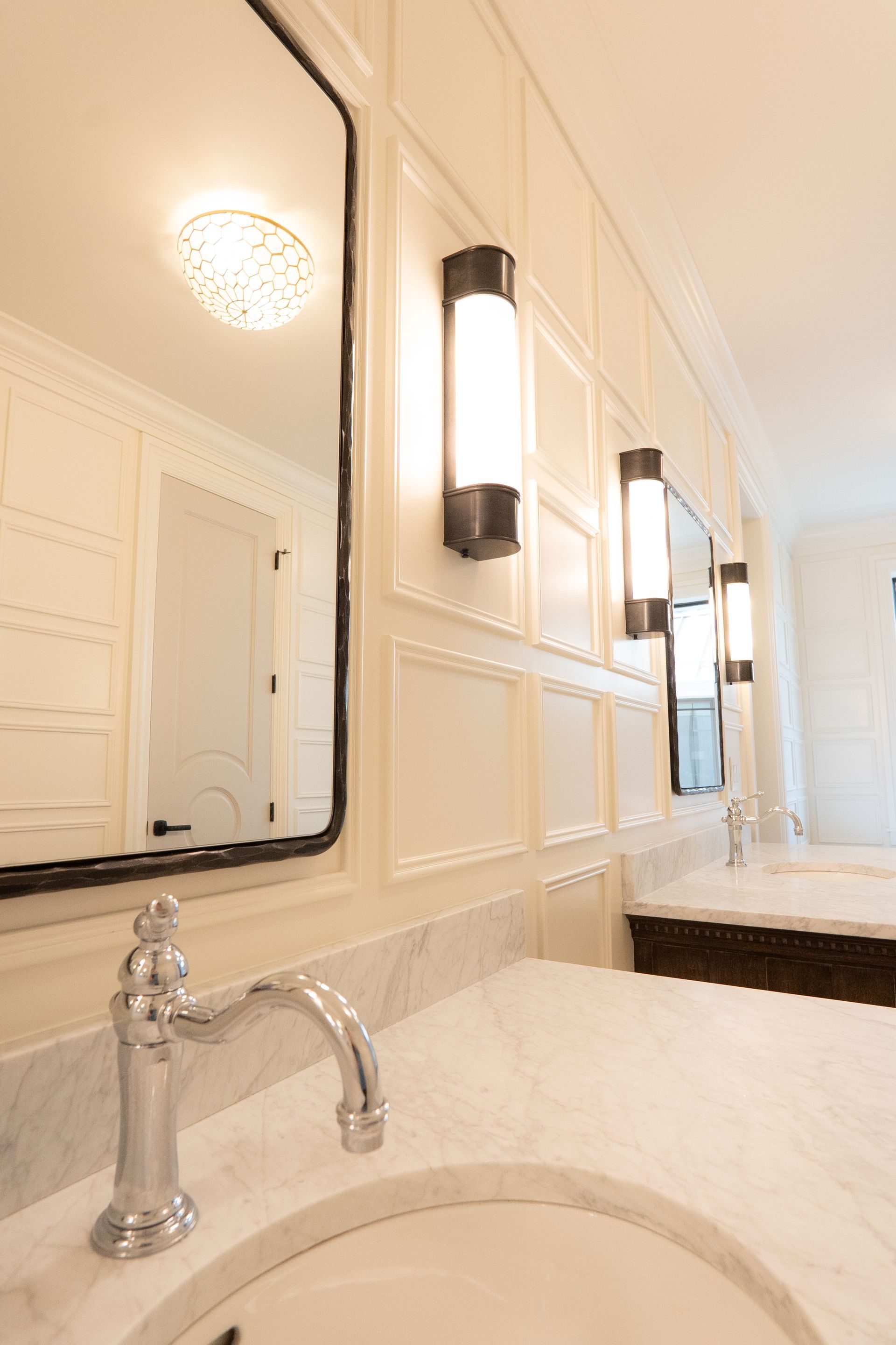 A bathroom with two sinks , mirrors , and lights.
