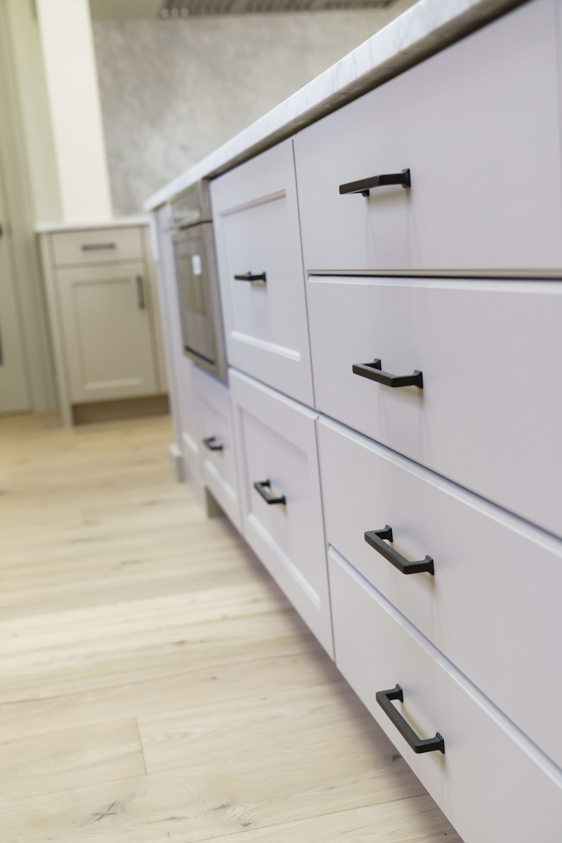 A kitchen with white cabinets and black drawer handles.