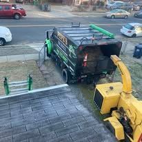 A garbage truck and wood chipper next to a driveway.