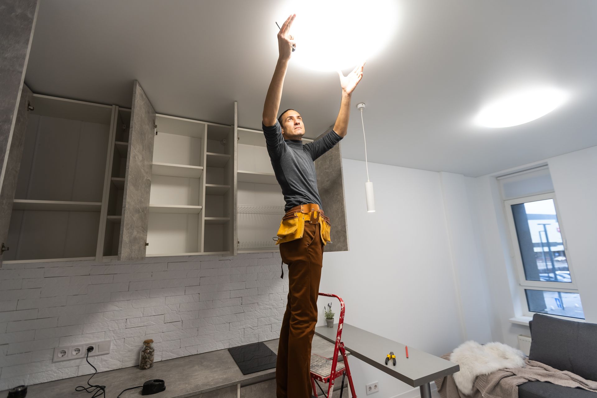 Electrical contractor installing a ceiling light fixture. Electrical contractor installing a ceiling light fixture.